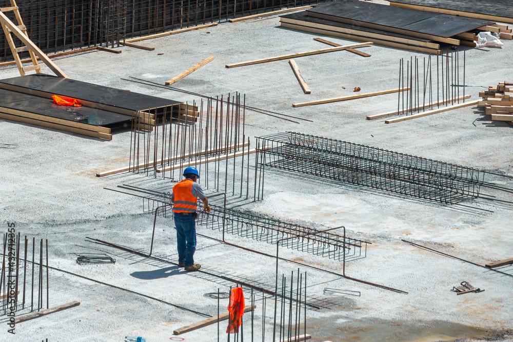 Naklejka premium Workers make metal reinforcement for the concrete foundation.