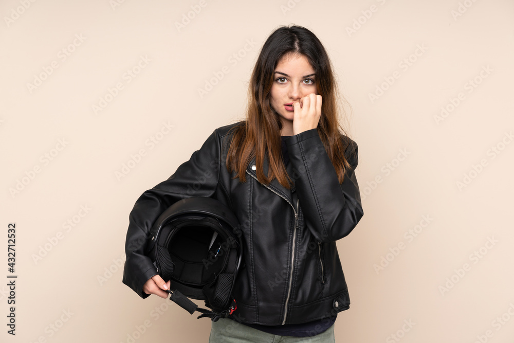 Woman with a motorcycle helmet isolated on beige background nervous and scared Woman with a motorcycle helmet isolated on beige background nervous and scared