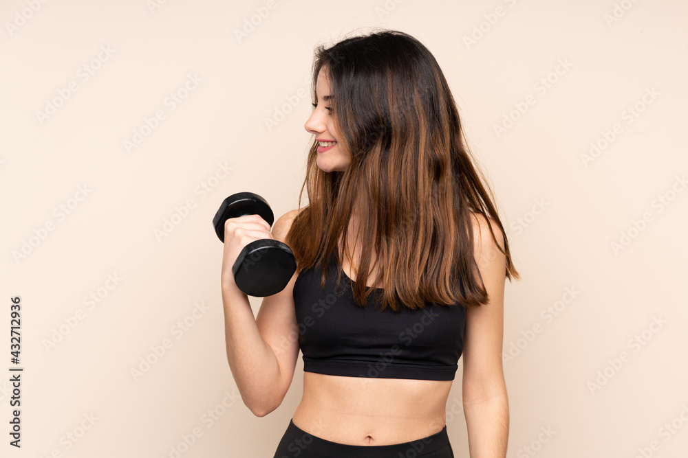 Young sport woman making weightlifting isolated on beige background looking to the side Young sport woman making weightlifting isolated on beige background looking to the side