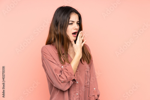 Young caucasian woman isolated on pink background yawning and covering wide open mouth with hand