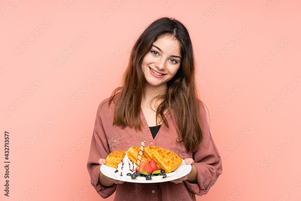 Young caucasian woman holding waffles isolated on pink background smiling a lot Young caucasian woman holding waffles isolated on pink background smiling a lot