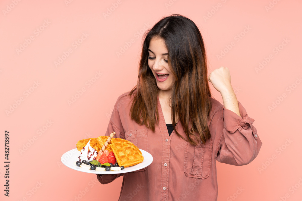 Young caucasian woman holding waffles isolated on pink background celebrating a victory Young caucasian woman holding waffles isolated on pink background celebrating a victory