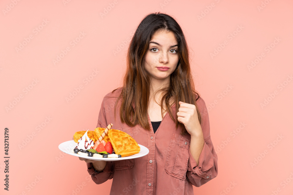 Young caucasian woman holding waffles isolated on pink background with sad expression Young caucasian woman holding waffles isolated on pink background with sad expression