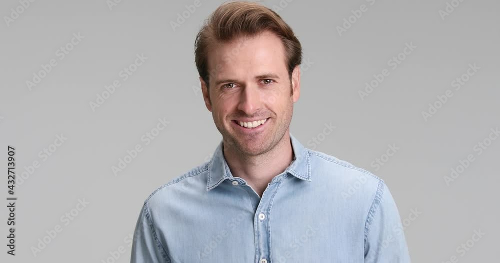 happy young casual man wearing blue denim shirt moving and smiling on grey background in studio happy young casual man wearing blue denim shirt moving and smiling on grey background in studio