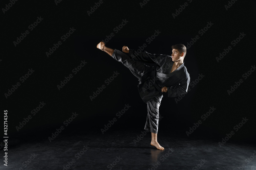 Male karateka, fighter in black kimono, training Male karateka, fighter in black kimono, training