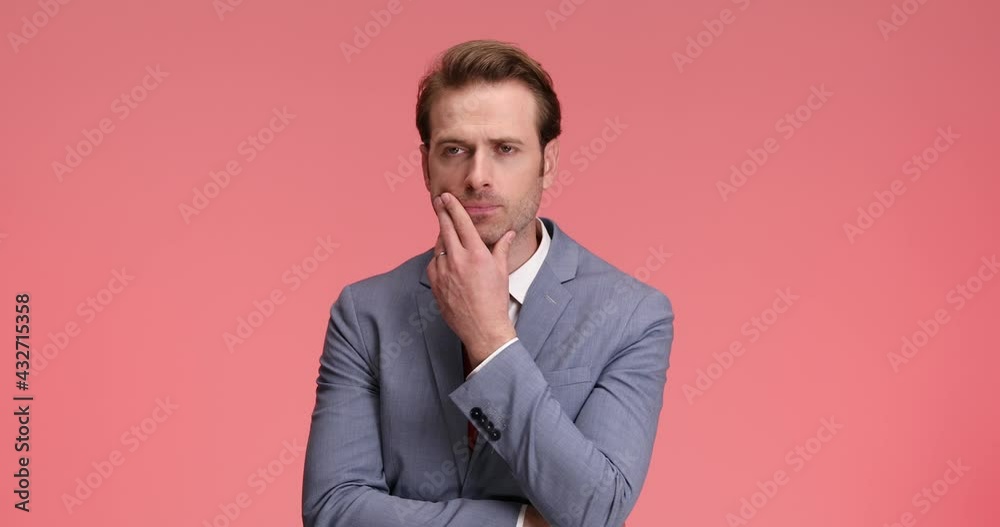 concerned man in elegant suit touching chin while trying to solve difficult problems, crossing arms and thinking on pink background in studio concerned man in elegant suit touching chin while trying to solve difficult problems, crossing arms and thinking on pink background in studio