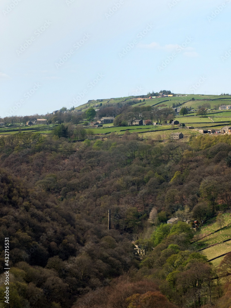 view along the colden valley in calderdale near hebden bridge with the village of colden on the hills above the woodland