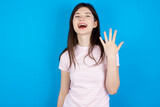 young beautiful Caucasian woman wearing stripped T-shirt over blue wall smiling and looking friendly, showing number five or fifth with hand forward, counting down