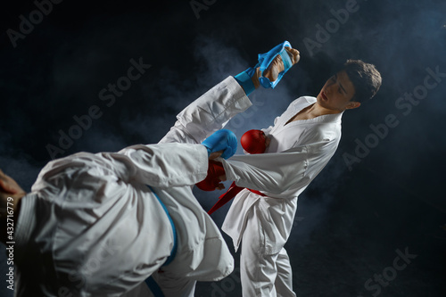 Two male karatekas in white kimono and gloves