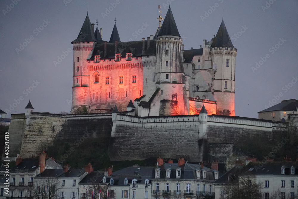 Christmas lighting at dusk on the old limestone castle of Saumur above the town in the Loire valley, France