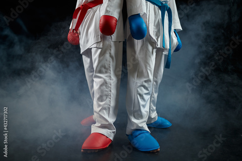 Two karatekas poses in white kimono and gloves
