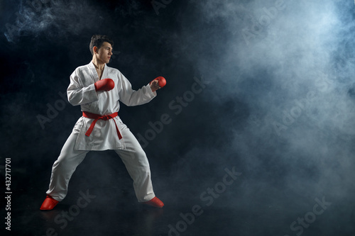 Male karate fighter in white kimono and red gloves