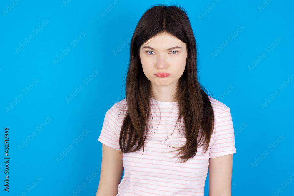young beautiful Caucasian woman wearing stripped T-shirt over blue wall depressed and worry for distress, crying angry and afraid. Sad expression. young beautiful Caucasian woman wearing stripped T-shirt over blue wall depressed and worry for distress, crying angry and afraid. Sad expression.