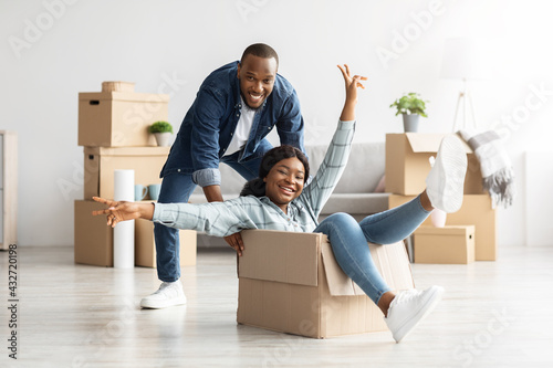 Cheerful married black couple having fun together while moving to new home