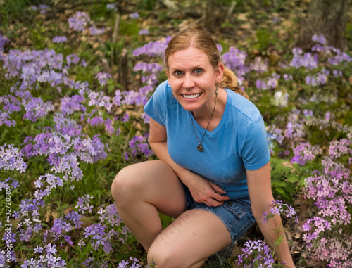 Portrait of smiling middle aged woman surrounded with purple wild flowers; spring in Midwest photo