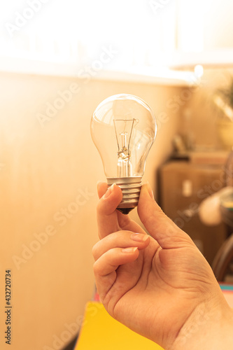 Lit light bulb in woman hand, creative and freelancer workplace in the background