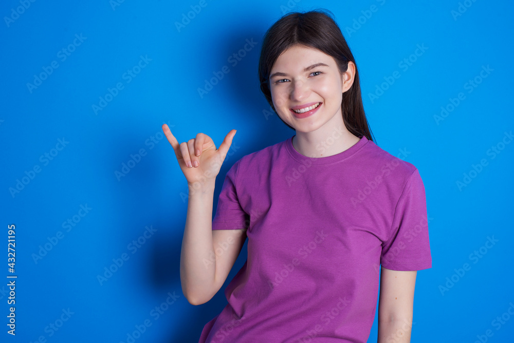 young beautiful Caucasian woman wearing purple T-shirt over blue wall showing up number six Liu with fingers gesture in sign Chinese language young beautiful Caucasian woman wearing purple T-shirt over blue wall showing up number six Liu with fingers gesture in sign Chinese language