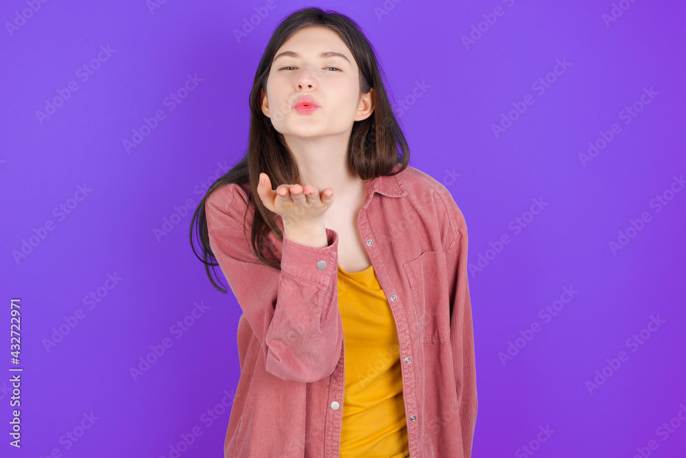 young beautiful Caucasian woman wearing casual clothes over purple wall looking at the camera blowing a kiss with hand on air being lovely and sexy. Love expression. young beautiful Caucasian woman wearing casual clothes over purple wall looking at the camera blowing a kiss with hand on air being lovely and sexy. Love expression.