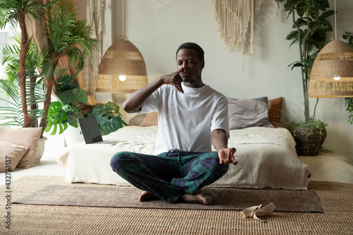Young african man practicing yoga lesson, doing Alternate Nostril Breathing exercise photo