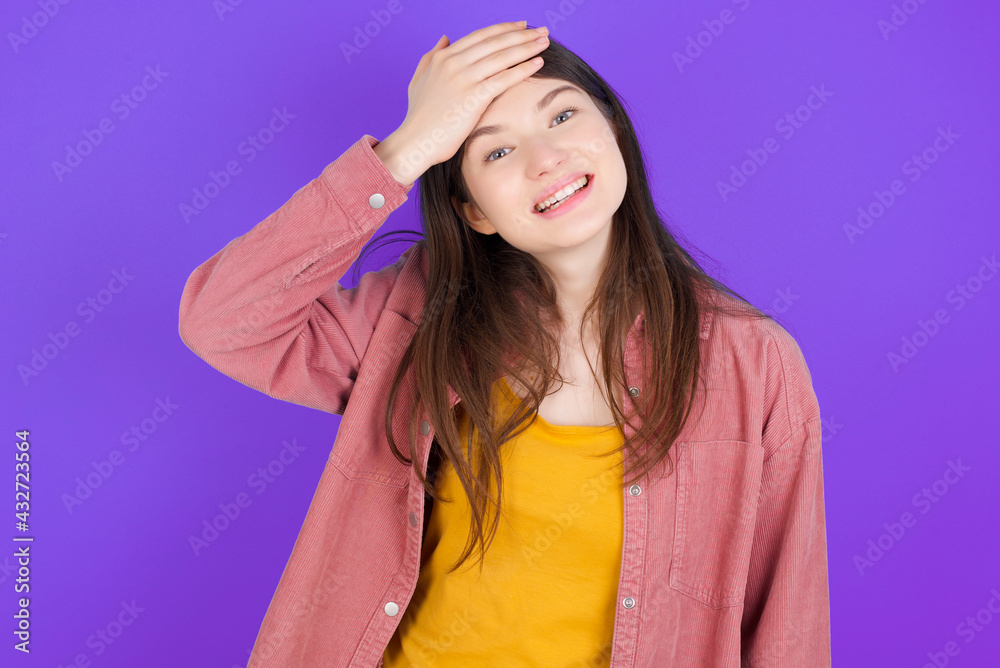 Oops, what did I do? young beautiful Caucasian woman wearing casual clothes over purple wall holding hand on forehead with frightened and regret expression. Oops, what did I do? young beautiful Caucasian woman wearing casual clothes over purple wall holding hand on forehead with frightened and regret expression.