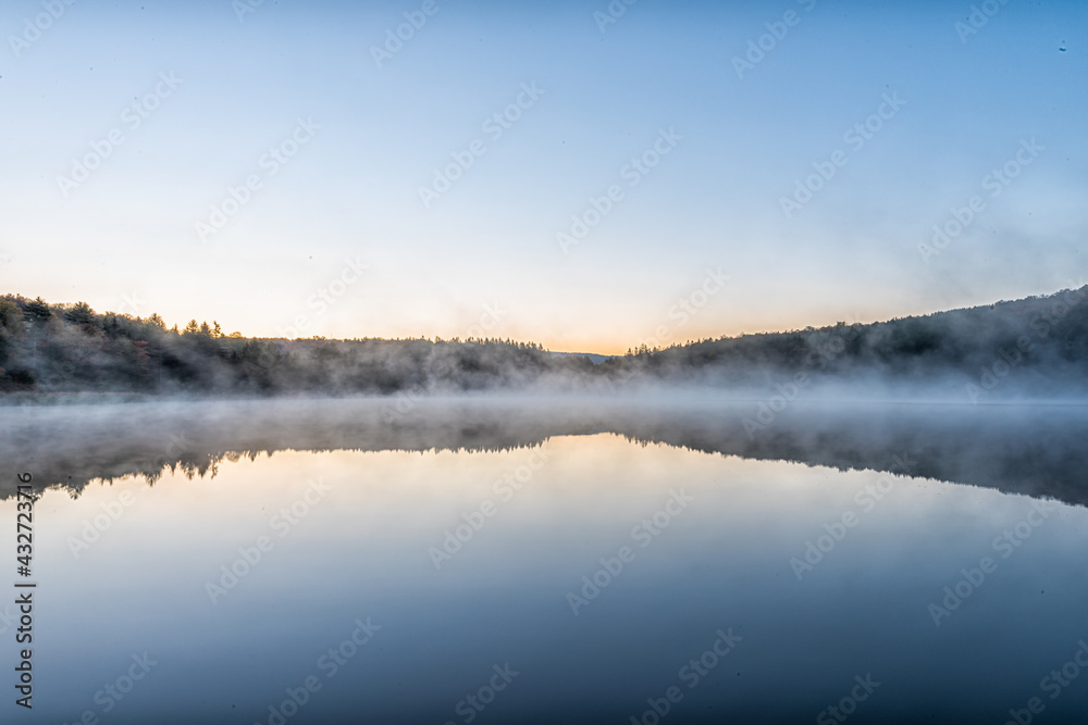 Spruce Knob Lake blue water in West Virginia at sunrise with yellow sunlight, nobody and landscape view of forest trees in autumn fall season