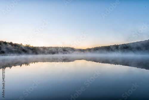 Spruce Knob Lake blue water in West Virginia at sunrise with yellow sunlight, nobody and landscape view of forest trees in autumn fall season © Kristina Blokhin