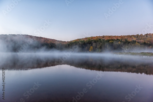 Fototapeta Naklejka Na Ścianę i Meble -  Spruce Knob Lake in West Virginia at sunrise with nobody and landscape view of blue water and forest trees in autumn fall season