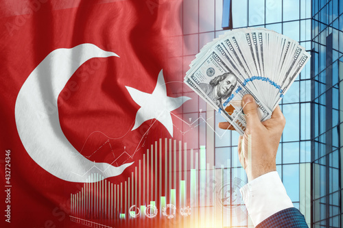 Fototapeta Naklejka Na Ścianę i Meble -  Money in a man's hand against the background of the flag of Turkey. Income of the Turks. Financial condition of residents of Turkey, taxes, loans, mortgages. State debt of the country.