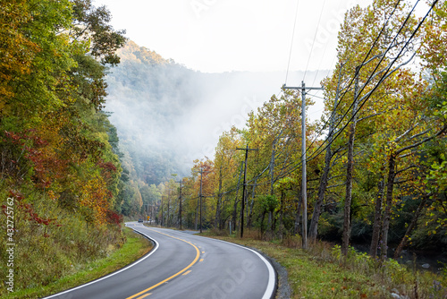 Foggy mist misty scenic highway in rural countryside West Virginia in fog fall autumn season with sunrise by winding road at Monongahela National Forest Appalachian mountains