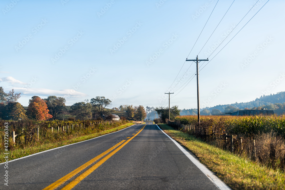 Roadside farmhouse house in countryside rural road highway in Virginia, USA by mountain forest with corn field and winery vineyard grape crop in colorful autumn at sunrise