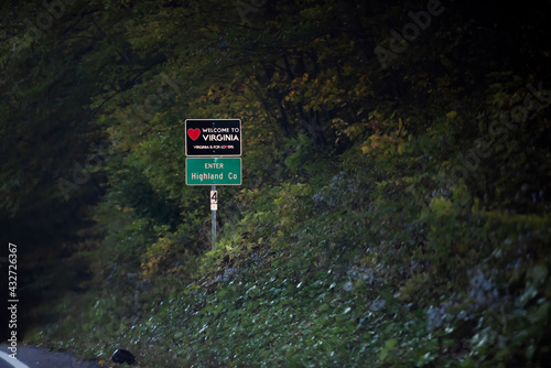 Red heart sign on highway in Virginia with welcome to state sign and is for lovers text logo in Highland county, VA