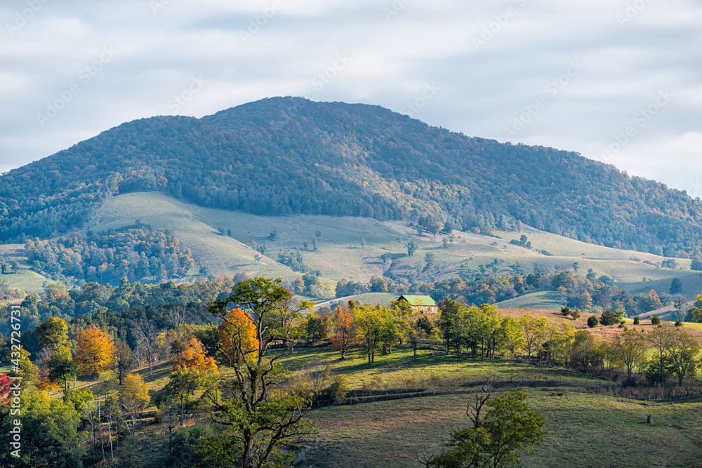 Obraz premium Autumn red maple trees landscape with mountains farm on rolling hills in small rural countryside town of Monterey and Blue Grass, Highland County, Virginia