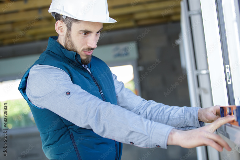 male builder checking window sill with spirit level male builder checking window sill with spirit level