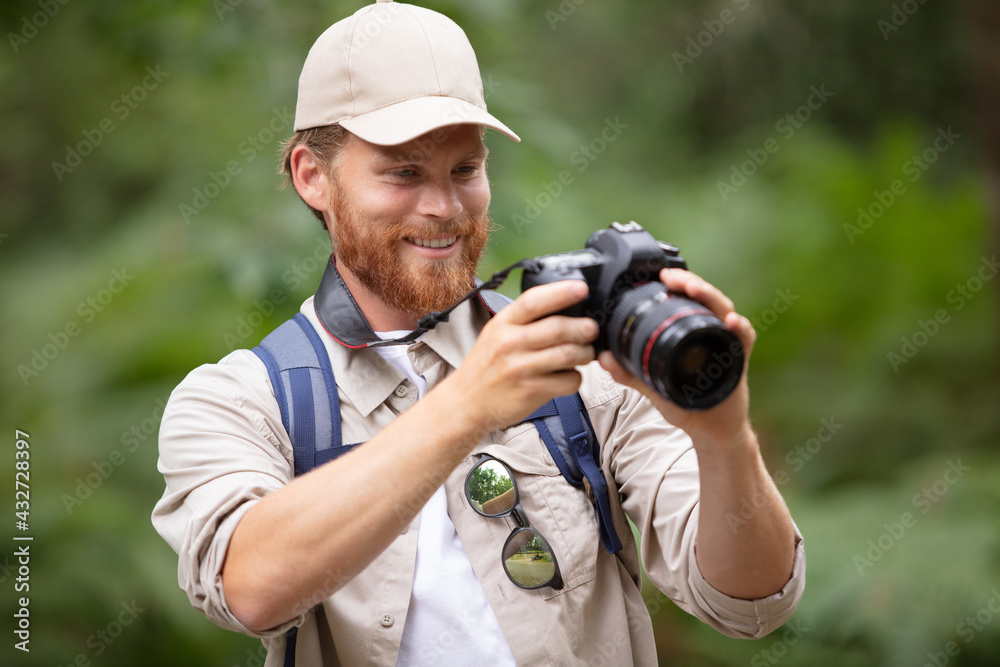 male photographer reviewing photos on camera in the countryside male photographer reviewing photos on camera in the countryside
