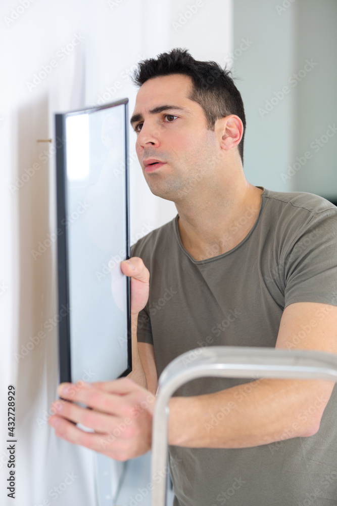 repairman putting picture frame onto wall