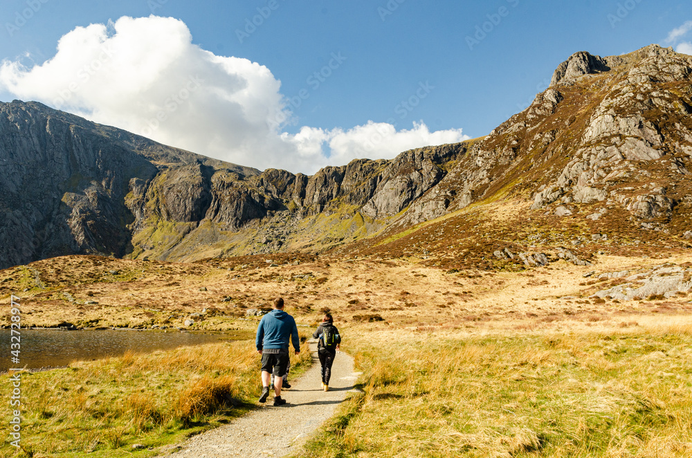 Group of hiking backpackers in Welsh mountains walking next to the lake Llyn Idwal.