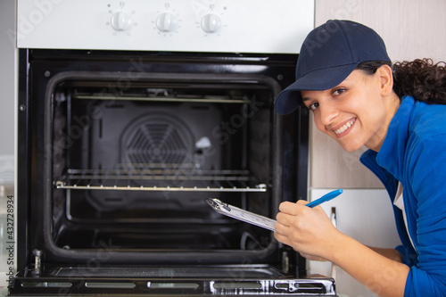 confident young repairwoman repairing oven