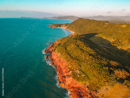 blue sea with green mountains at sunrise in Guarda do Embau - SC Brazil photo