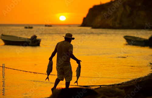 Fototapeta Naklejka Na Ścianę i Meble -  fisherman walking by the sea with catch on his hands