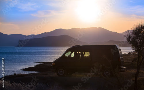 Minivan by the seashore at sunset against of mountains
