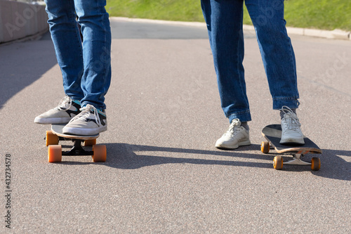female and male feet in white sneakers on skateboard on asphalt, on track. woman and man legs on board at skatepark. urban active extreme sport in the city.