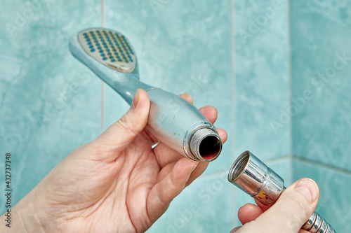 Tela Clogged shower head is detached from flexible hose to be replaced with new one