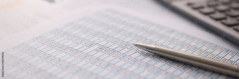 Ballpoint pen and calculator lying on documents with numbers closeup