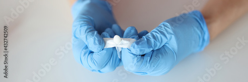 Doctors hands in rubber gloves opening rectal suppository closeup