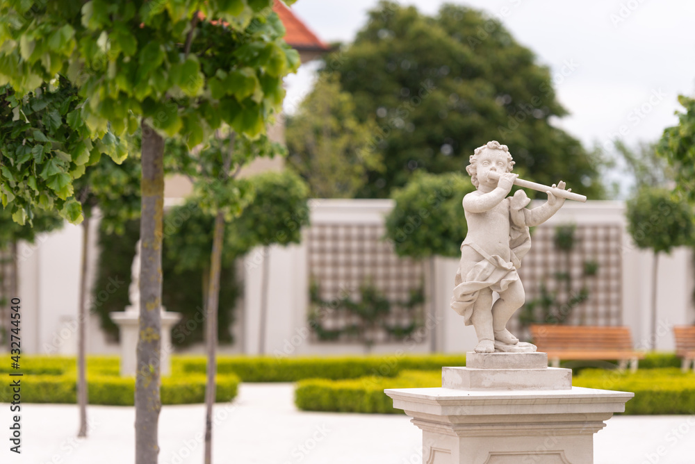 Obraz premium Bratislava Castle Park. White stone covered park. Green bushes, young trees and statues in the garden. Statue with a pipe.