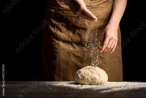 woman pouring flour powder on the dough with onion. Baking bread concept.