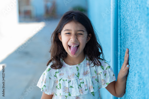 Uma criança, menina, brasileira dos cabelos pretos e lisos, fazendo careta com a língua de fora. photo