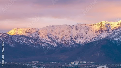 An amazing view of the snow covered Andes mountains fields with the sunlight coming from the sunset on a cloudy day. A time lapse view to see the clouds motion