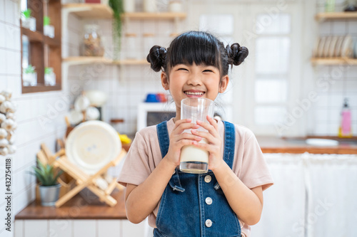 Portrait of Asian little young girl drinking milk in the kitchen.