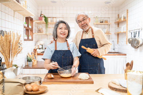 Portrait of Asian senior couple standing in the kitchen cooking bakery